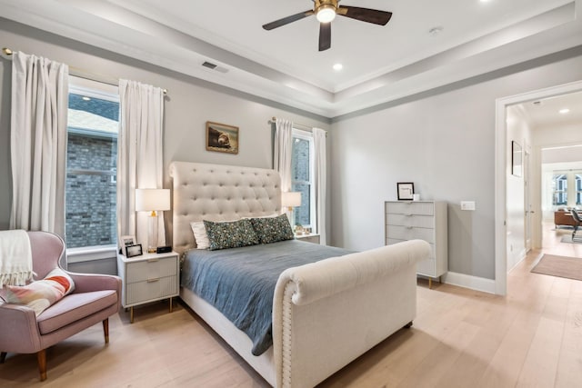 bedroom with a tray ceiling, light hardwood / wood-style flooring, and ceiling fan