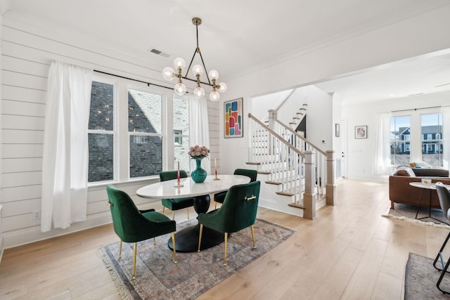 dining area featuring ornamental molding, light hardwood / wood-style flooring, and a notable chandelier