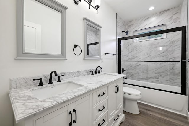 full bathroom with vanity, hardwood / wood-style flooring, toilet, and combined bath / shower with glass door