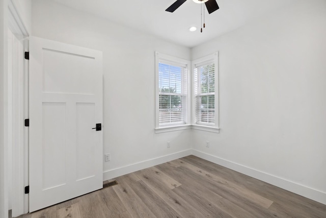 empty room with ceiling fan and light hardwood / wood-style flooring