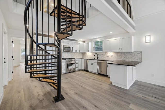 kitchen with white cabinetry, appliances with stainless steel finishes, light hardwood / wood-style flooring, and plenty of natural light