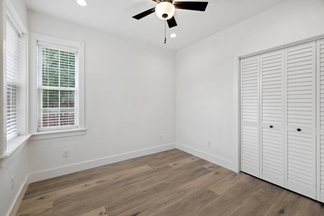 unfurnished bedroom with ceiling fan, light wood-type flooring, and a closet