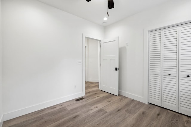 unfurnished bedroom with ceiling fan, light hardwood / wood-style floors, and a closet