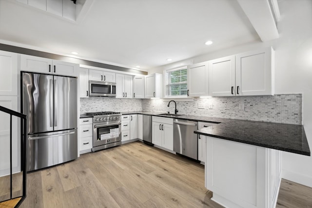 kitchen featuring white cabinetry, sink, kitchen peninsula, and appliances with stainless steel finishes