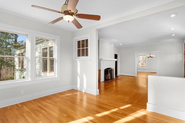 unfurnished living room with hardwood / wood-style flooring, crown molding, a brick fireplace, and ceiling fan with notable chandelier