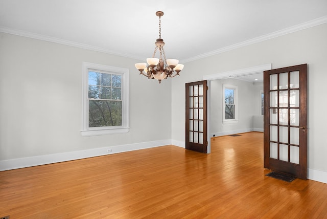 spare room with ornamental molding, french doors, a chandelier, and light wood-type flooring