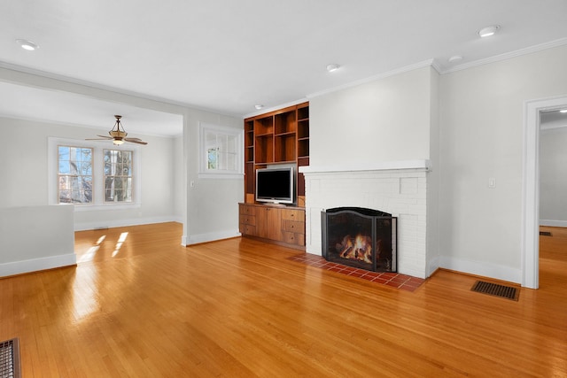 unfurnished living room featuring a brick fireplace, ornamental molding, ceiling fan, and light wood-type flooring