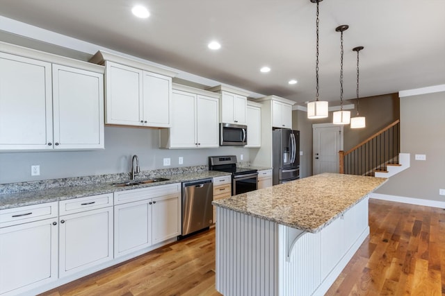 kitchen with a breakfast bar, a center island, appliances with stainless steel finishes, pendant lighting, and white cabinets