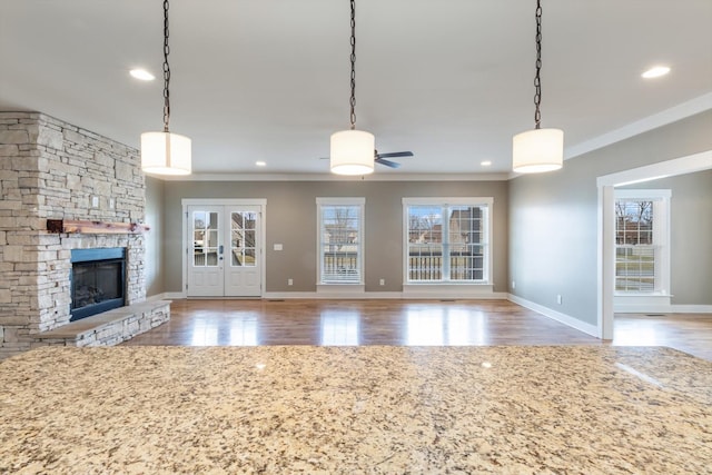 unfurnished living room with a fireplace, a wealth of natural light, hardwood / wood-style floors, and french doors