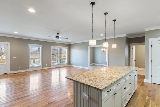 kitchen with a kitchen island, white cabinetry, hanging light fixtures, light stone countertops, and light hardwood / wood-style flooring