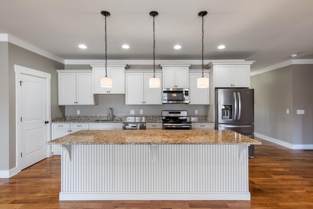 kitchen with sink, appliances with stainless steel finishes, white cabinetry, hanging light fixtures, and a kitchen island