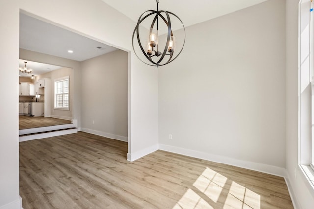 empty room featuring a notable chandelier and light hardwood / wood-style floors