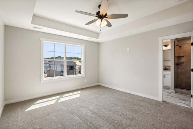 carpeted spare room featuring ceiling fan and a tray ceiling