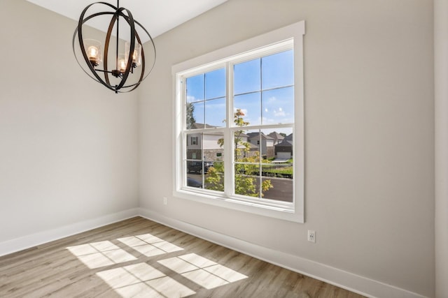 unfurnished dining area with light hardwood / wood-style flooring and a notable chandelier