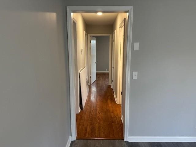 hallway with dark wood-style flooring and baseboards