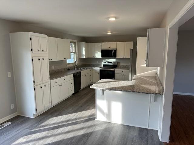 kitchen featuring dark wood finished floors, appliances with stainless steel finishes, white cabinets, a sink, and a peninsula