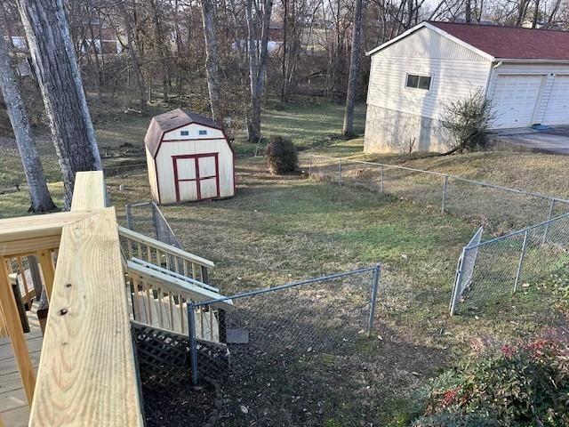 view of yard featuring a garage, an outdoor structure, a storage shed, and fence