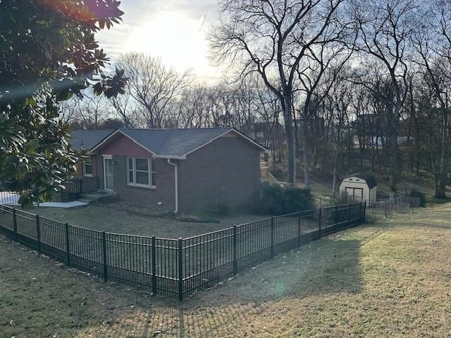 view of side of property with fence private yard, an outdoor structure, a lawn, and a storage unit