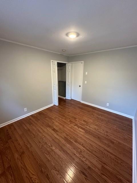 unfurnished bedroom with dark wood-style floors, ornamental molding, a closet, and baseboards