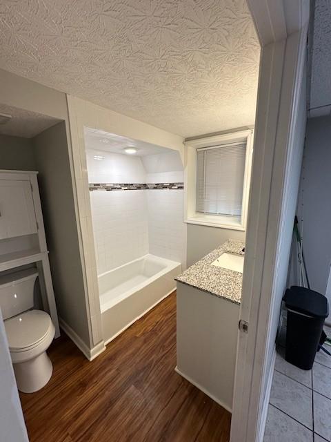 full bathroom with vanity, hardwood / wood-style floors, a textured ceiling, and toilet