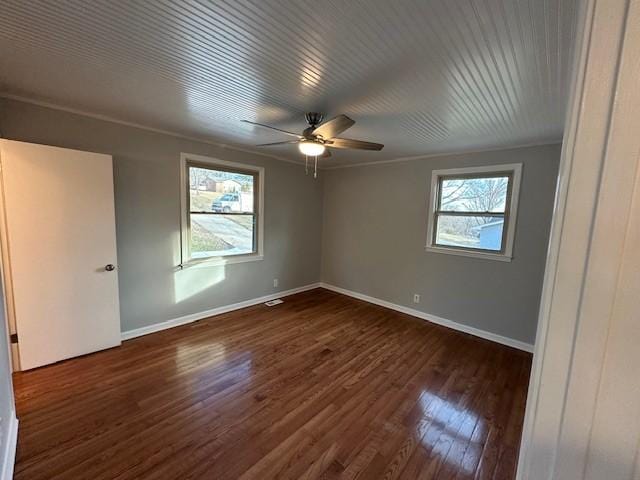 unfurnished bedroom with baseboards, multiple windows, ornamental molding, and dark wood-type flooring