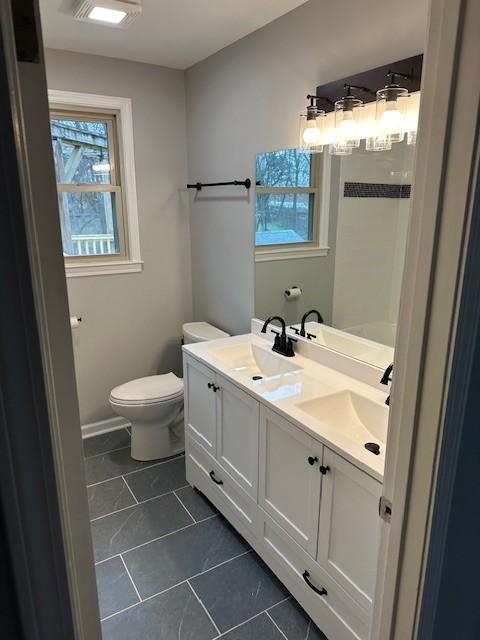 bathroom featuring double vanity, tile patterned flooring, toilet, and a sink