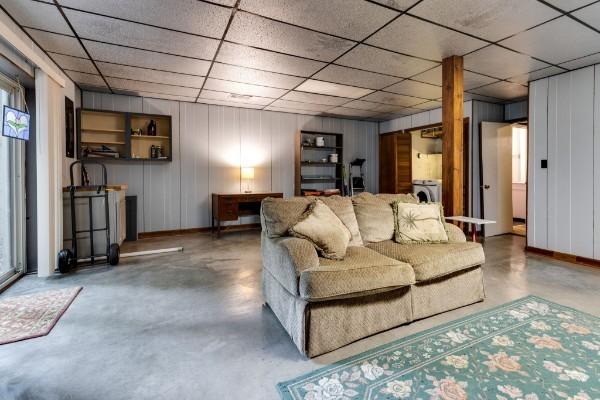 living room featuring a paneled ceiling and concrete floors