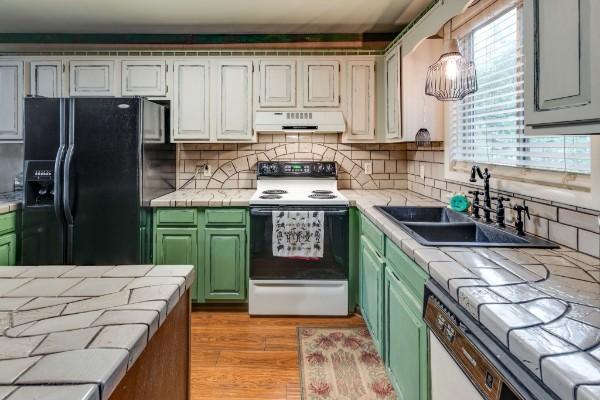 kitchen featuring black fridge with ice dispenser, sink, white cabinetry, green cabinets, and electric stove