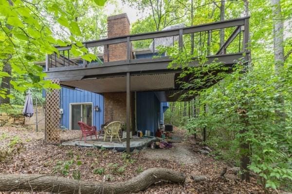 rear view of house featuring a wooden deck and a patio