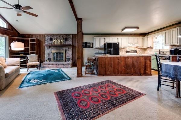 carpeted living room featuring ceiling fan, lofted ceiling, a wealth of natural light, and a fireplace