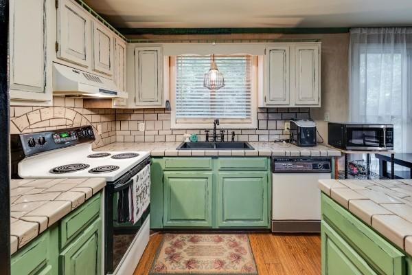 kitchen with white cabinetry, sink, tile countertops, and white appliances