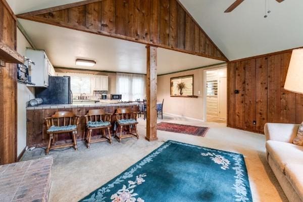 interior space featuring ceiling fan, wooden walls, and high vaulted ceiling