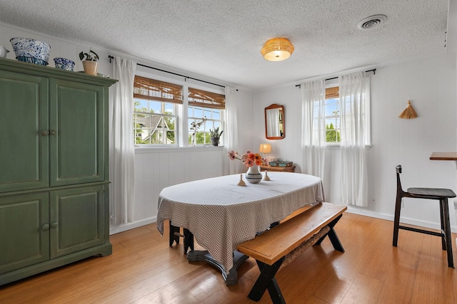 dining room featuring a textured ceiling, light hardwood / wood-style flooring, and a wealth of natural light