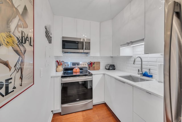 kitchen with white cabinetry, stainless steel appliances, sink, and tasteful backsplash