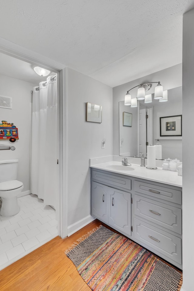 bathroom with vanity, hardwood / wood-style floors, a textured ceiling, and toilet