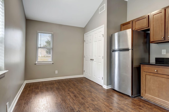 kitchen featuring stainless steel refrigerator, dark hardwood / wood-style flooring, and vaulted ceiling