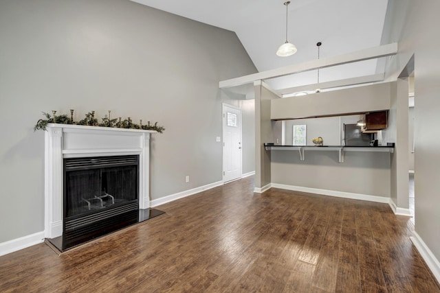 unfurnished living room featuring a fireplace with raised hearth, vaulted ceiling, baseboards, and wood finished floors