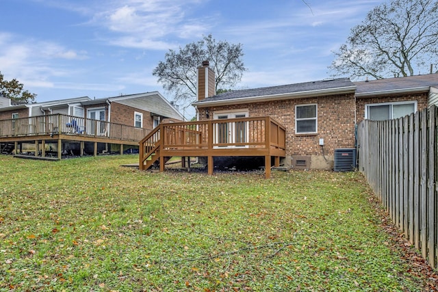 back of property with a wooden deck, cooling unit, and a lawn