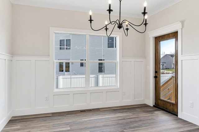 unfurnished dining area featuring hardwood / wood-style floors and a chandelier