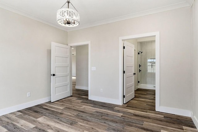 unfurnished bedroom with an inviting chandelier, ensuite bath, ornamental molding, and dark hardwood / wood-style floors