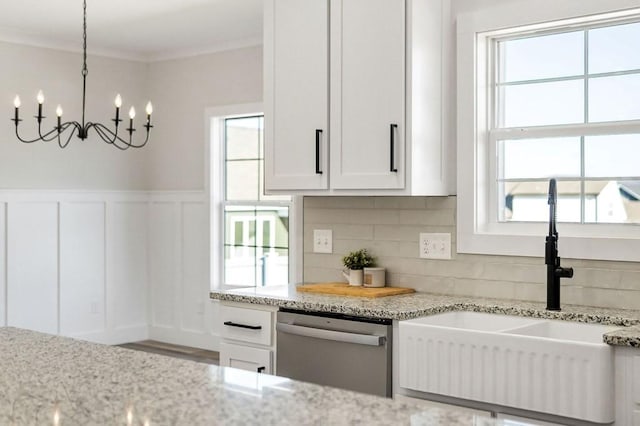 kitchen with sink, white cabinets, hanging light fixtures, stainless steel dishwasher, and light stone counters