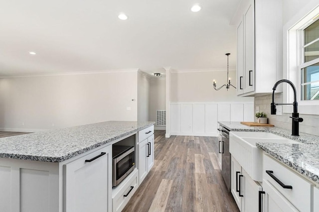 kitchen with pendant lighting, sink, white cabinetry, stainless steel appliances, and a center island