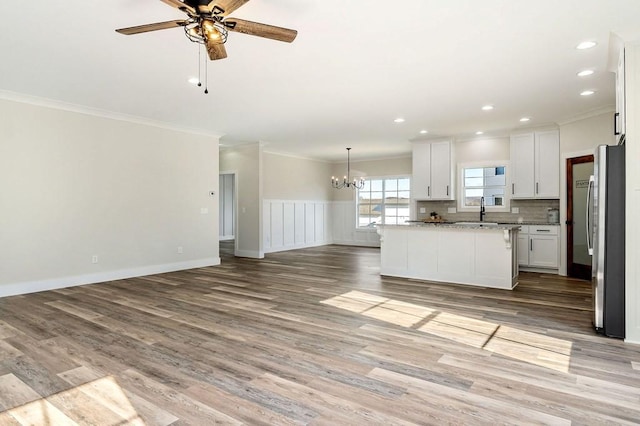 kitchen featuring a center island, light wood-type flooring, stainless steel refrigerator, light stone countertops, and white cabinets