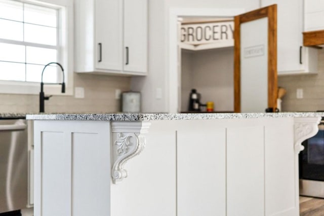 kitchen with stove, stainless steel dishwasher, and white cabinets