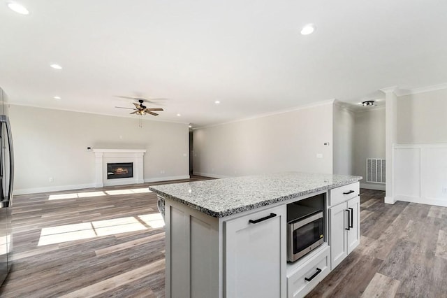 kitchen featuring crown molding, light stone counters, light hardwood / wood-style floors, white cabinets, and a kitchen island