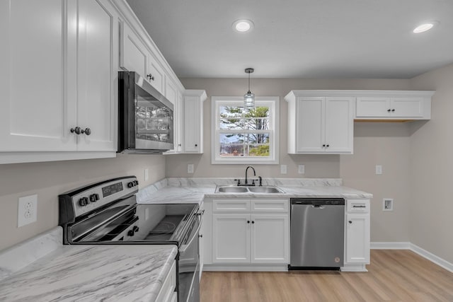 kitchen with white cabinetry, sink, hanging light fixtures, stainless steel appliances, and light wood-type flooring