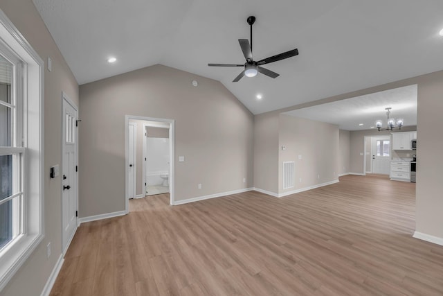 unfurnished living room featuring ceiling fan with notable chandelier, vaulted ceiling, and light hardwood / wood-style floors