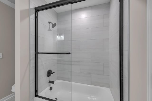 bathroom featuring toilet and combined bath / shower with glass door