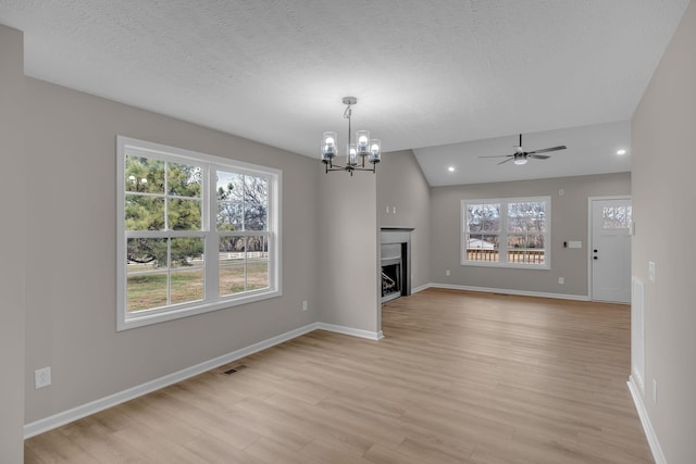 unfurnished living room with lofted ceiling, light hardwood / wood-style flooring, and a textured ceiling