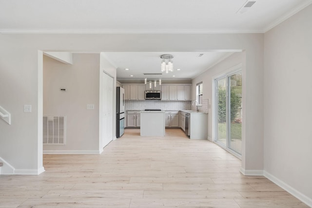 kitchen featuring sink, backsplash, ornamental molding, stainless steel appliances, and light wood-type flooring